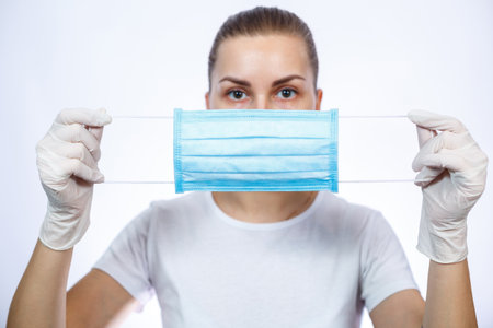 woman health worker in protective medical surgical mask against the virus. Isolated on white...