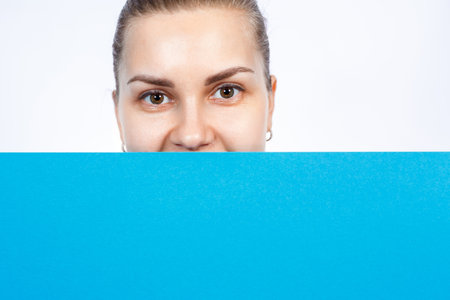 A girl in a white T-shirt holds in her hands a blue blank large sheet of banner.の写真素材