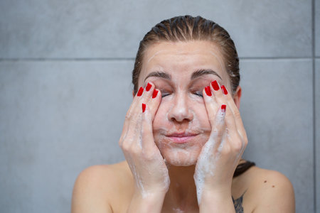 Facial skin care. A woman washes her face after makeup with soap. Girl using a cleanser cosmetic...