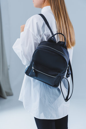 Black leather backpack in a woman's hand. A man with a luxurious leather backpack. Women's bagsの写真素材