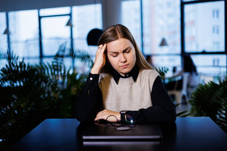 Young beautiful woman businesswoman suffers a headache from overwork. migraine at workの写真素材
