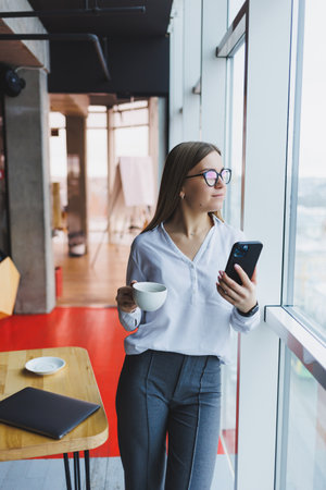 Portrait of a young and successful woman solving business problems during a telephone conversation, sitting in a modern cafe. Cute interior is enjoying his free time in the cafe.の写真素材