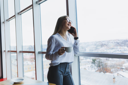 Portrait of a young and successful woman solving business problems during a telephone conversation, sitting in a modern cafe. Cute interior is enjoying his free time in the cafe.の写真素材