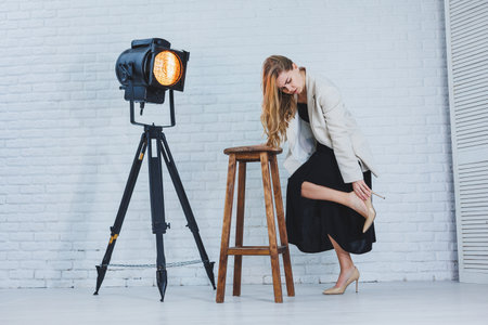 Young woman with pain in her legs after wearing high heels, close up. A woman in a black dress and jacket.の写真素材