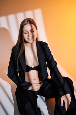 Smiling pregnant woman in a black suit on a gray background. Beautiful elegant pregnant woman.の写真素材