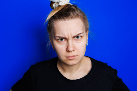 Portrait of a young woman on a blue background holding her head. Headache, migraine in a woman.