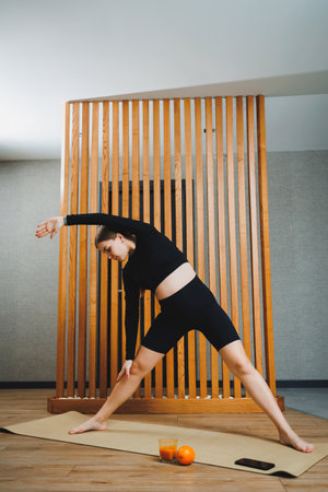 Pregnant woman doing sports on mat at home. Young pregnant woman doing stretching and yoga at home. Activity during pregnancyの写真素材