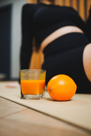 A glass of freshly squeezed orange juice on the background of a young woman. Useful juice for a woman's body. Vitamin citrus freshの写真素材
