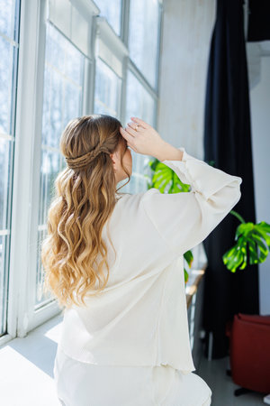 Beautiful hairstyle on long blond hair, woman with curls on her head. Elegant women's hairstyle with...