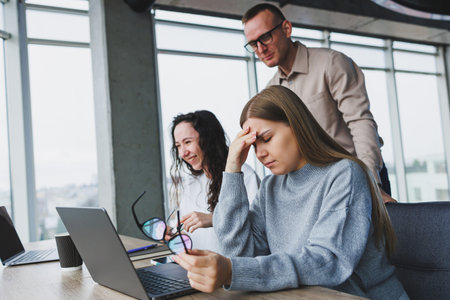 Young business woman typing on a keyboard, researching digital designs for a new advertising project, sitting in a chic office. Headache from working in the officeの写真素材