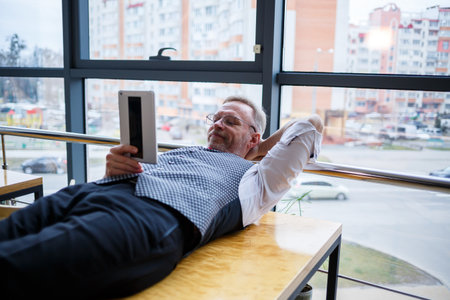Adult male businessman resting and looking at a tablet in search of ideas for a project to develop new technologiesの写真素材