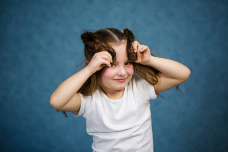 little girl in a white t-shirt and jeans fooling around with her hairの写真素材