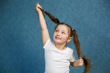 little girl in a white t-shirt and jeans fooling around with her hair