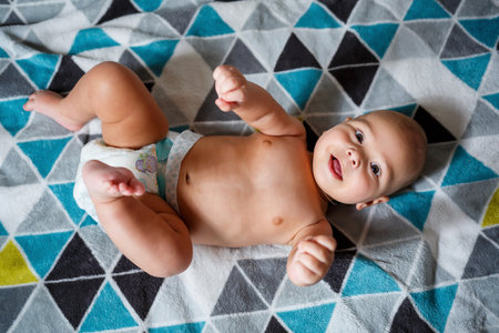 little boy age 8 months and is smiling. He wears a diaper. Health and development of children