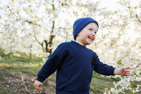 A three-year-old boy runs through a blooming garden. Cheerful emotional child is walking in the park.の写真素材