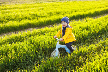Happy emotional child. A cheerful boy walks on a children's jogging track on the green grass in the garden. Running track for childrenの写真素材