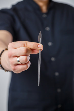 Doctor specialist holds a metal surgical scalpel in his handsの写真素材