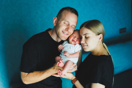 Happy mom and dad hold their newborn baby in their arms. Young mother and father hug a newborn baby. Young family and newborn baby at home.の写真素材