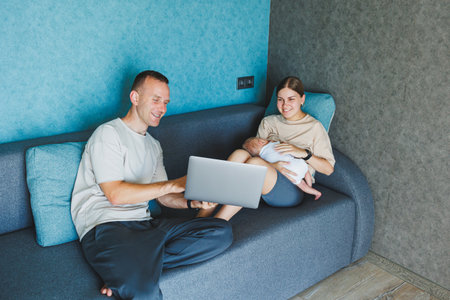 Happy family mom, dad and cute baby son having fun using laptop at home. Young parents and funny toddler child boy spending lifestyle time at computer sitting on couchの写真素材