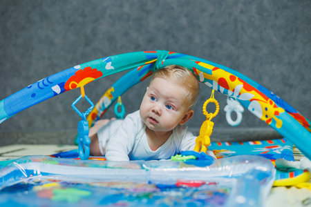 A baby is lying on a playmat. The baby learns to hold his head. Development of a newborn child