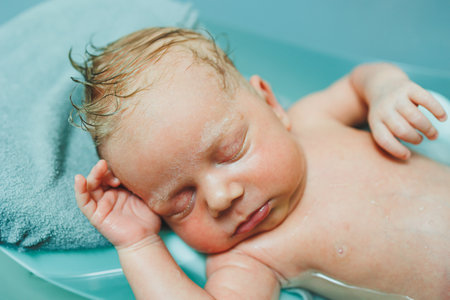 A newborn baby lies on a stand in a bathtub for bathing. Bathing the baby. Hygiene of newborns and children.の写真素材