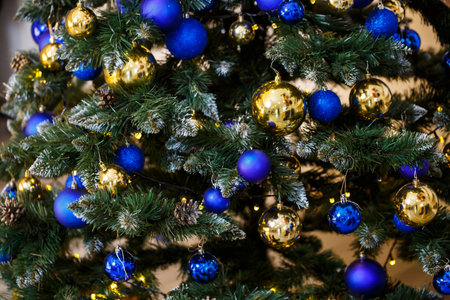 Decorated Christmas tree close-up. Blue and gold balls and garland lights. Christmas balls on the...
