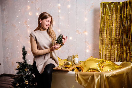 Happy woman in New Year's room. New Year's decoration of the room in golden color. The concept of the holiday and festive design. Home decor for the New Year.の写真素材