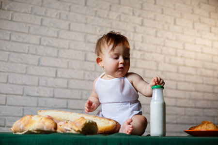 Little boy in a cap and with bread. Little child dressed as a cook in the kitchen.の写真素材