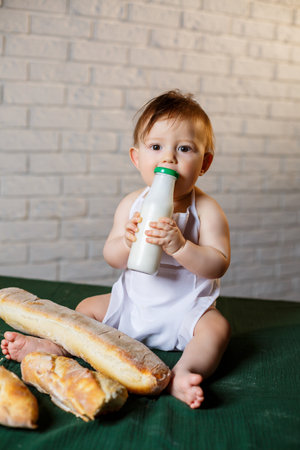 Little boy in a cap and with bread. Little child dressed as a cook in the kitchen.の写真素材
