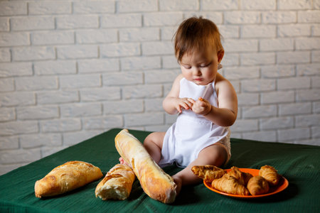 Little boy in a cap and with bread. Little child dressed as a cook in the kitchen.の写真素材
