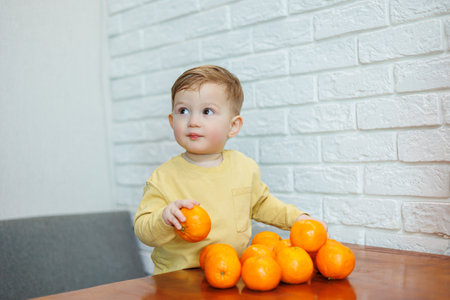 Little boy 2 years old eats tangerines. The kid wants to sit on citrus fruits for the first time. Healthy fruits for childrenの写真素材