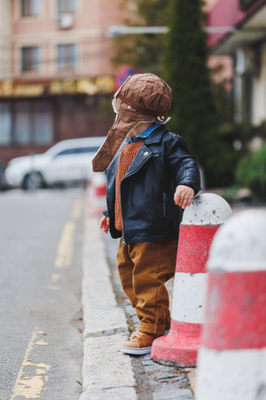 Stylish boy 3 years old in a leather jacket and brown trousers walks on the street. Modern child. Children's fashion. Happy childの写真素材