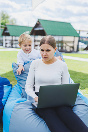 Cute young mother and son looking at laptop. Happy family, mother and son are resting in the park. A woman on maternity leaveの写真素材