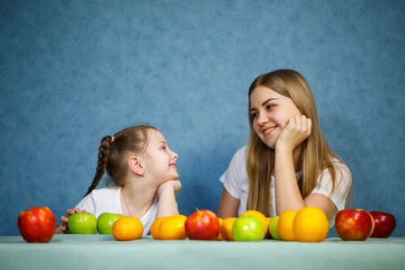 Little girl and mom play with fruits and fool around. They are wearing t-shirtsの写真素材