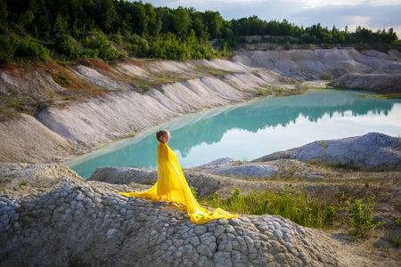 Beautiful blonde girl posing in a yellow dress in nature. Summer photo. Blue sky. Sunny day.