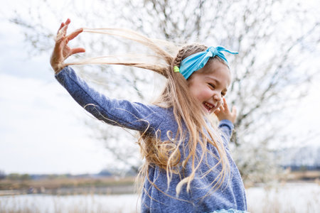 Adorable little girl playing in blooming apple tree garden on Easter egg hunt, runing and smiling. Child in spring fruit orchard with cherry blossom.の写真素材