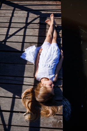 Portrait of a little girl outdoors in the summer by the lake. Little girl in summer dress by the river.の写真素材