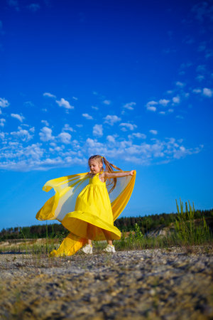 The symbol of freedom is a Ukrainian girl of 7 years old, patriotically dressed in a yellow dress against a blue sky. Blue sky. Sunny day. Free Ukrainian child. Child symbol of Ukraineの写真素材