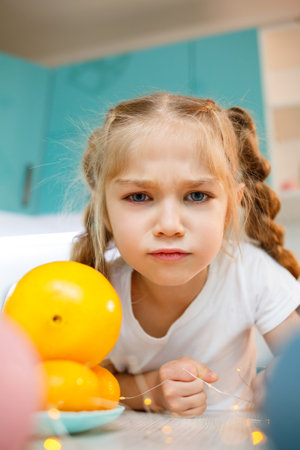 A girl of seven years old is wearing a white T-shirt. Plays with ripe tangerinesの写真素材