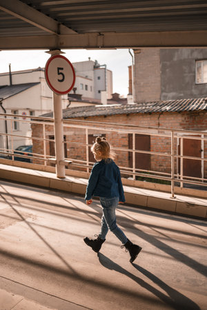 Stylish beautiful girl of about seven in a denim jacket walks on the streetの写真素材