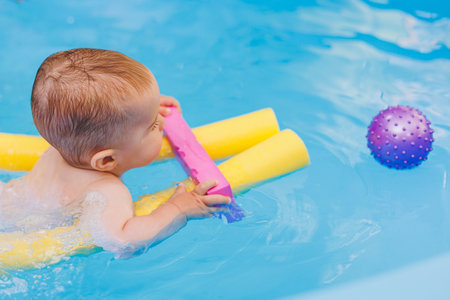 A little boy is learning to swim in a baby pool. Children's development. First swimming lessons for childrenの写真素材