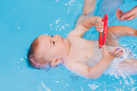 A little boy is learning to swim in a baby pool. Children's development. First swimming lessons for...