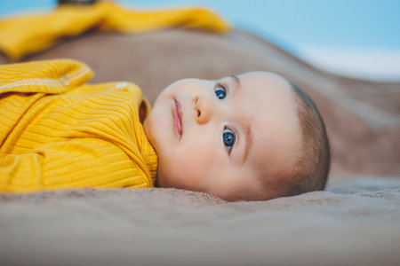 A happy baby of four months lies on a knitted blanket. Baby portrait. child holding his headの写真素材