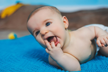A happy baby of four months lies on a knitted blanket. Baby portrait. child holding his head