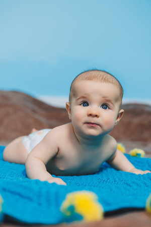 A happy baby of four months lies on a knitted blanket. Baby portrait. child holding his headの写真素材