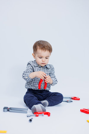 A cute boy in a shirt in the image of a builder, on a white background. Childhood, learning, work, games, career, imitation. Little daddy's helper.の写真素材