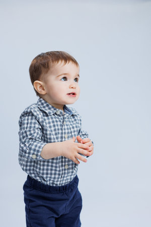 A little boy one year old on a white background in a checkered shirt. A small child with a smile on his face.の写真素材