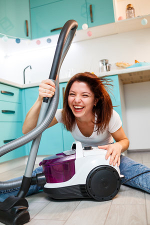 Young woman housewife plays with a vacuum cleaner. Fun apartment cleaningの写真素材