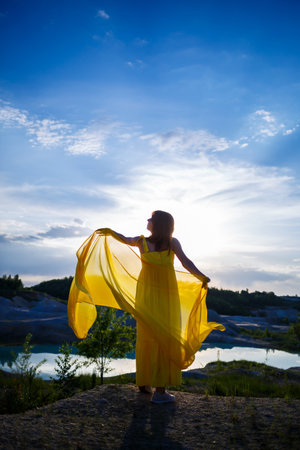 Summer lifestyle of stunning happy woman running in nature. In a long yellow dress. Romantic mood. Enjoying the sunshine. Sunny day. Selective focusの写真素材