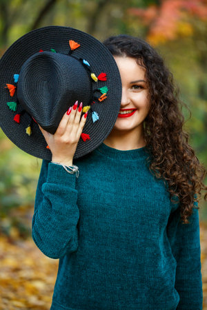 girl in the autumn forest with a hat in her hands